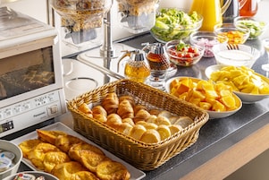 Un bufé con diversas opciones de comida, incluyendo pan, frutas y ensaladas.