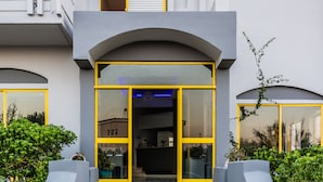 A modern two-story building with a stone staircase leading to a glass entrance. - Nereides Hotel (Platanias)