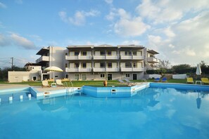 Ein modernes Hotel mit Schwimmbad, mehreren Balkonen und Sitzgelegenheiten im Freien.