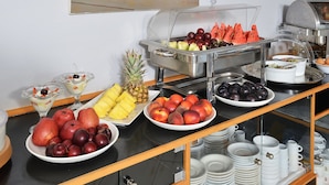 A buffet with various fruits and dishes, including apples, peaches, and watermelon slices. - Nereides Hotel (Platanias)