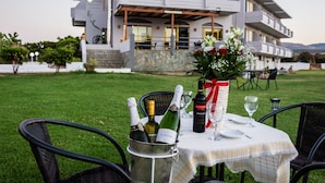 A dining setup with a table set outdoors, a metal bucket with bottles, and a vase with flowers. - Nereides Hotel (Platanias)