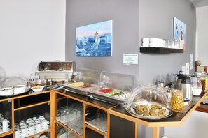 Ein reichhaltiges Buffet mit verschiedenen Speisen, einer Kaffeemaschine und einem Gemälde an der Wand.