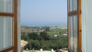 Ventana abierta con vistas a un paisaje costero, que incluye edificios y vegetación.