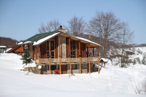 A log cabin with a stone foundation, large windows, and a wooden porch. - Sfendamos Wood Village (Naousa)