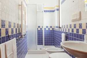A bathroom with blue and white tiles, a white sink, and a shower stall.