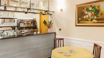 A restaurant with a bar area, a coffee machine, and a table set for two with a yellow tablecloth.