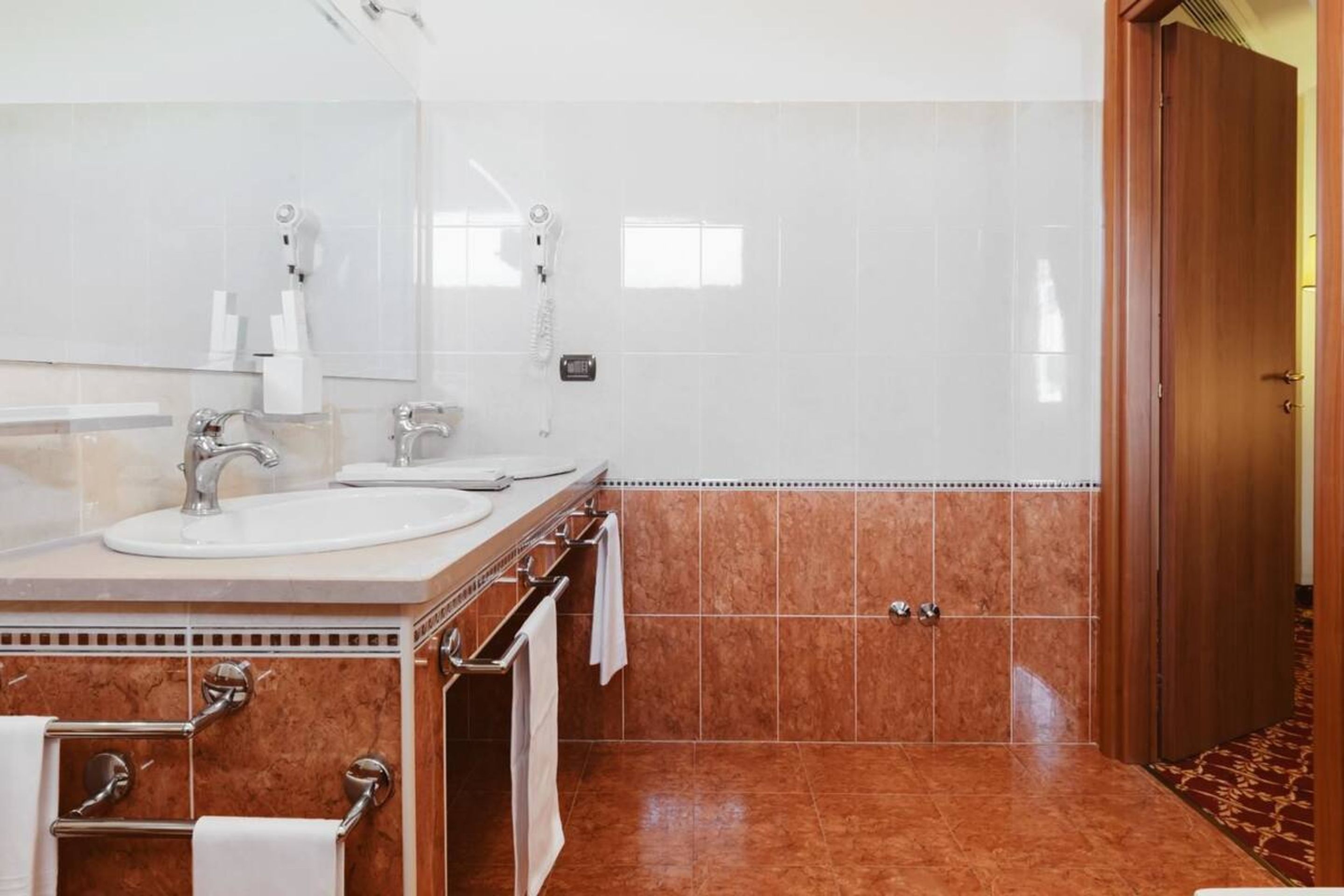 A modern bathroom with a large mirror, two sinks, and a shower.