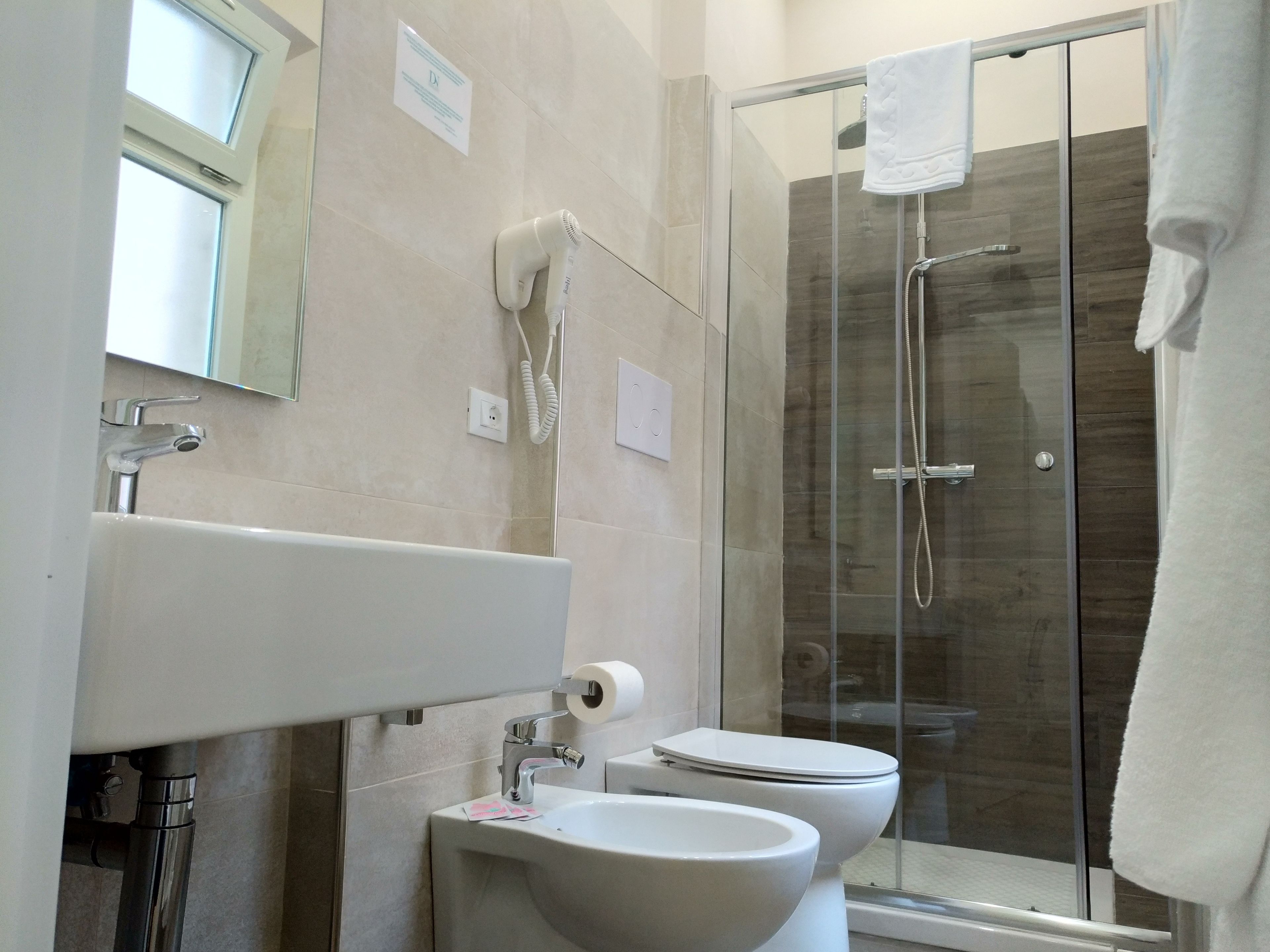 Een moderne badkamer met een douchecabine van glas, een wastafel en een toilet.