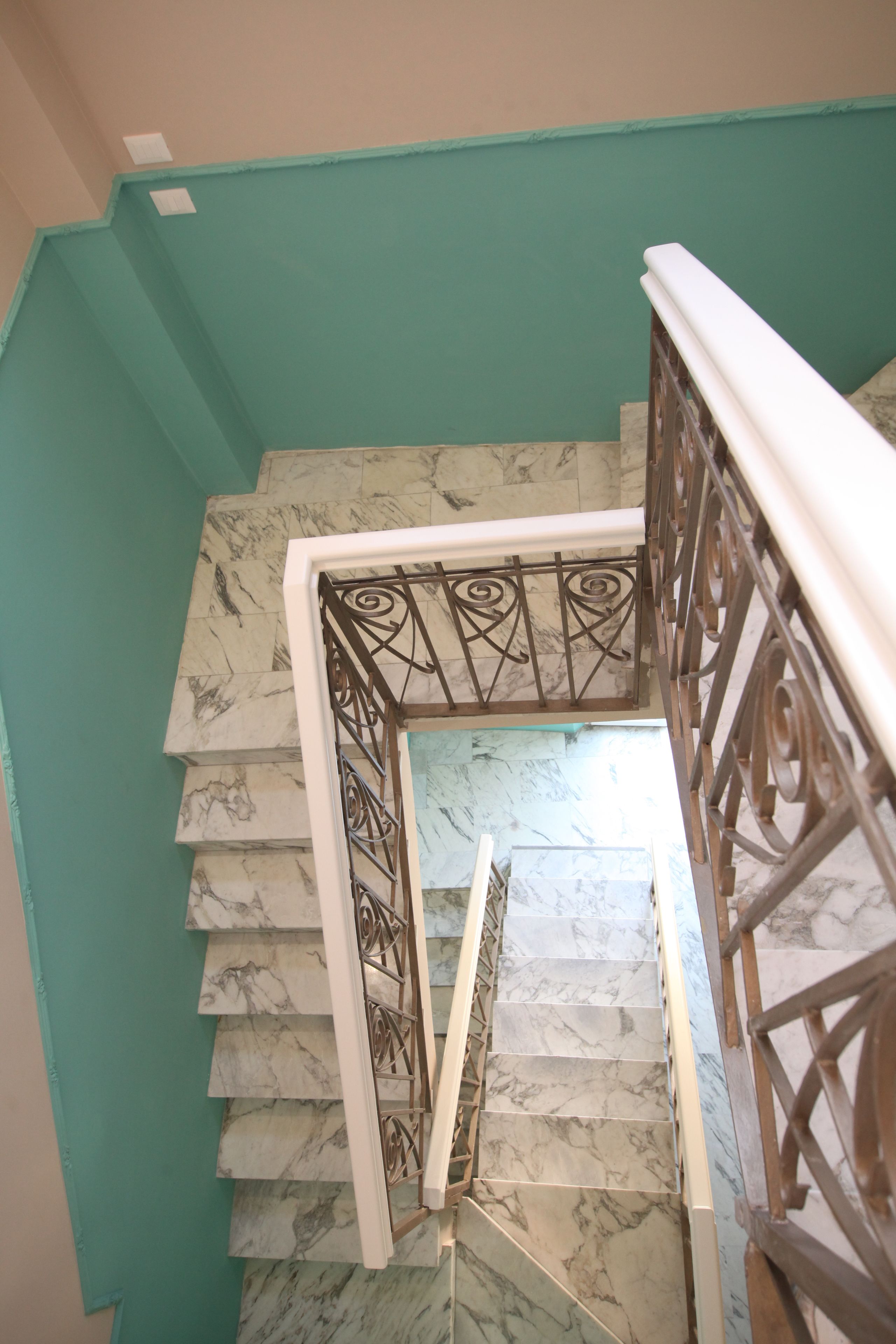 Una escalera con escalones de mármol y una pared color turquesa.