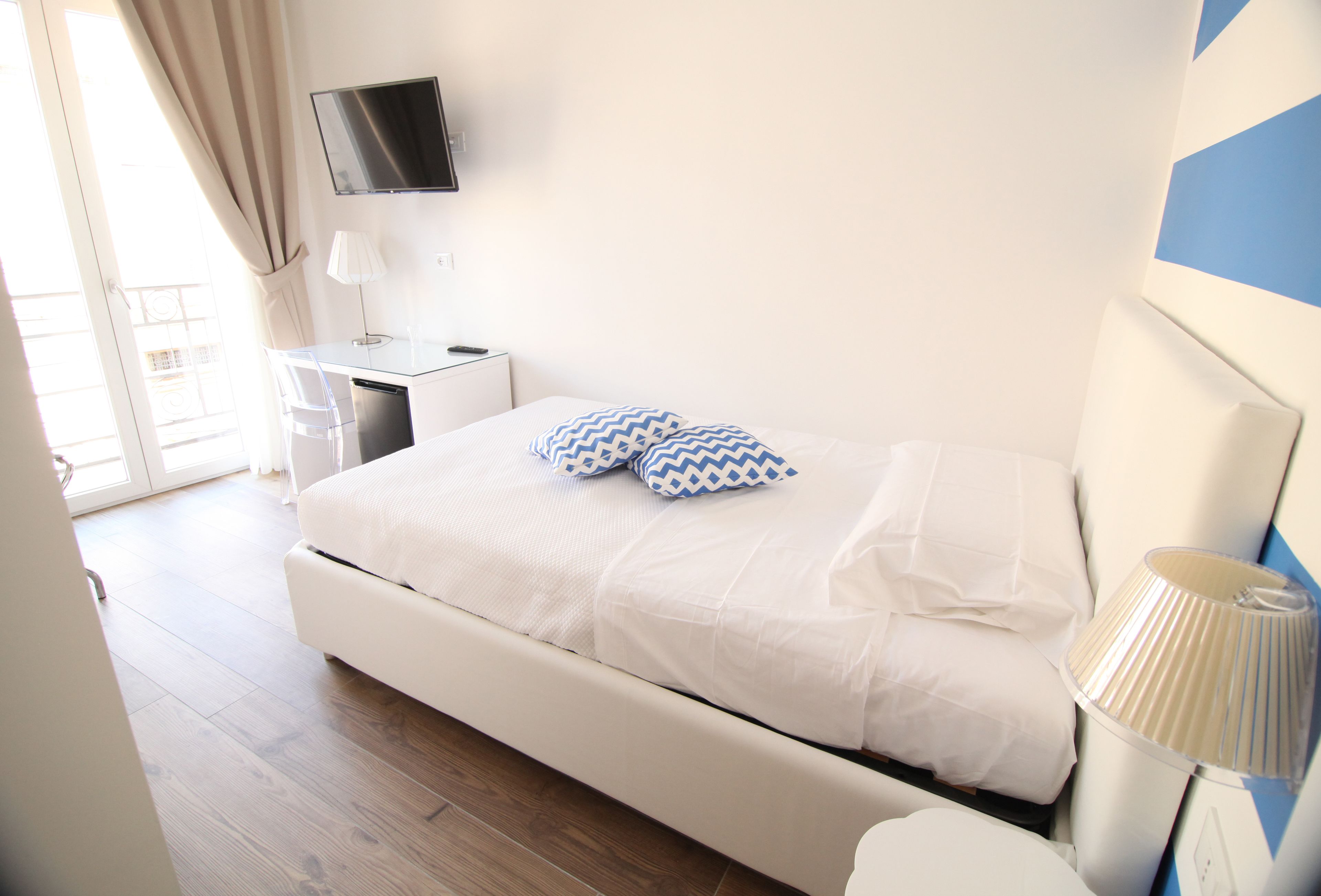 Une chambre à coucher moderne avec un lit, une table de chevet, une lampe et un téléviseur fixé au mur.