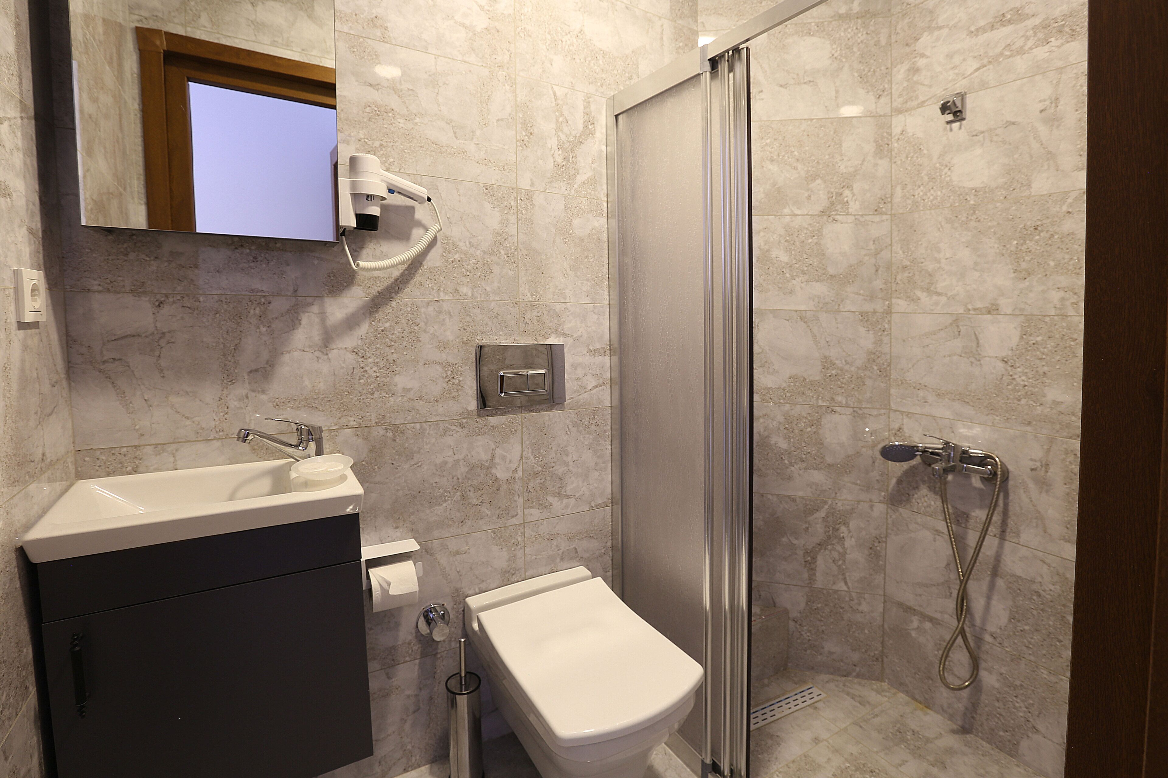 A modern bathroom with a shower, toilet, and sink.