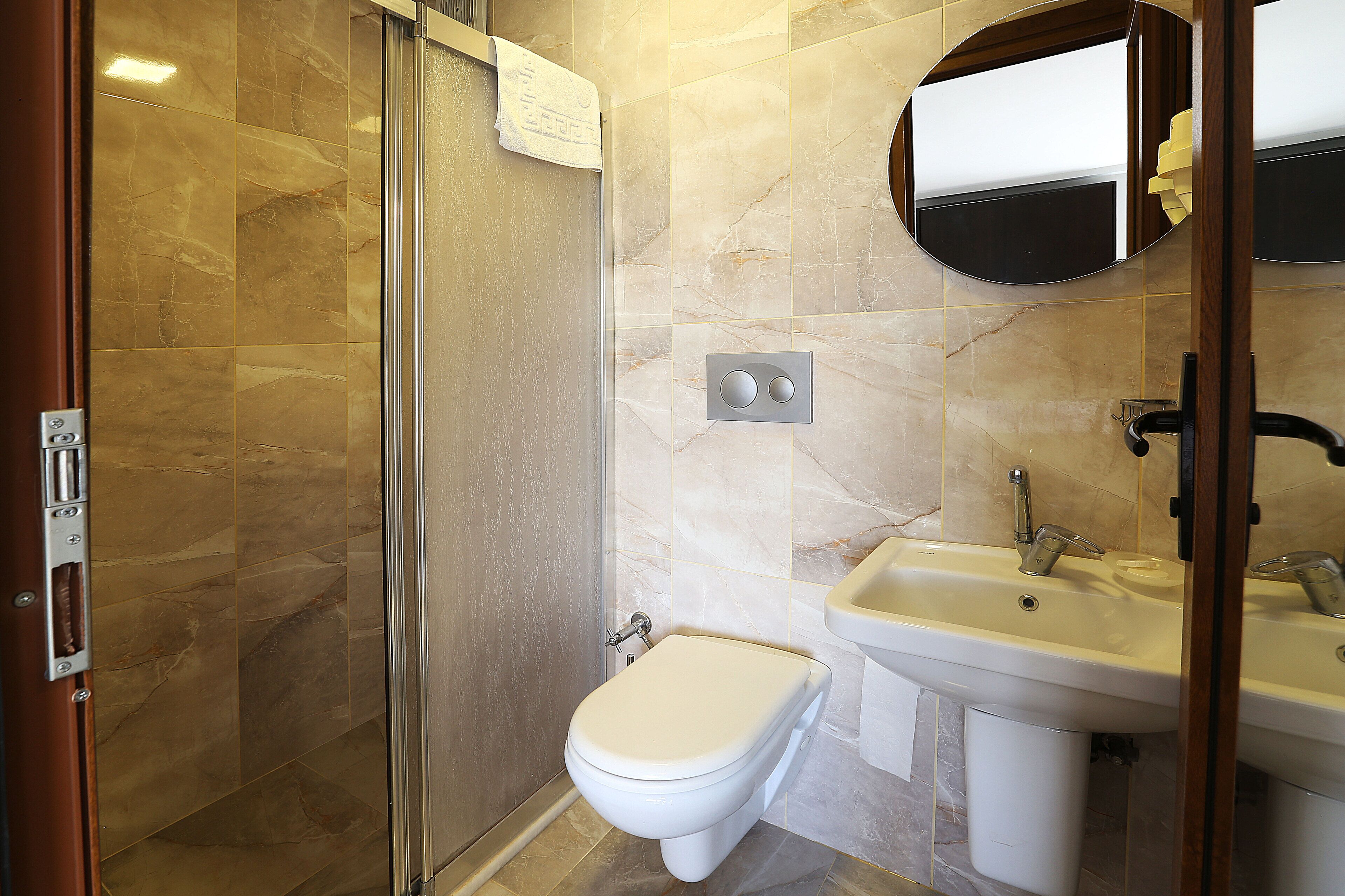 A bathroom with a toilet, sink, and a glass shower enclosure.