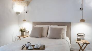 A neatly arranged bedroom with a bed, bedside tables, and a tray with cups and a teapot.