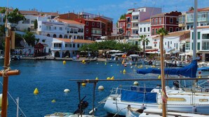 A marina with boats docked, surrounded by colorful buildings with red and white facades. - Hotel Nou Sant Antoni (Ciutadella de Menorca)