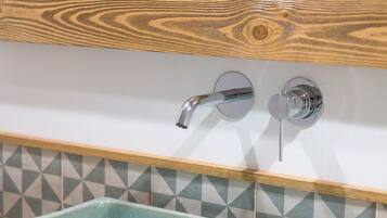 A bathroom with a rectangular ceramic sink, a wooden cabinet above, and a tiled backsplash.