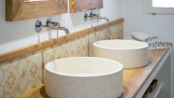 A bathroom with two round ceramic sinks, wooden vanity, and a mirror with a wooden frame.
