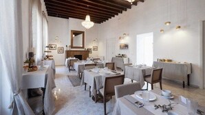 A dining area with multiple tables set for service, a chandelier, and a mirror on the wall. - Hotel Nou Sant Antoni (Ciutadella de Menorca)