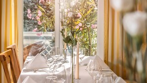 A dining table set with white tablecloth, glassware, and a vase with flowers. - ROEWERS Privathotel & Spa (Sellin)