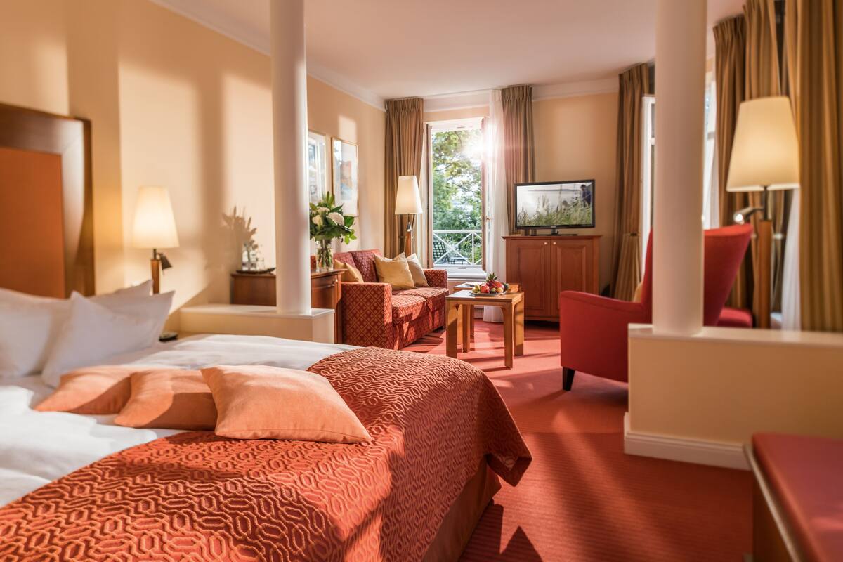 A hotel room with a large bed, a sofa, a TV, and a desk.