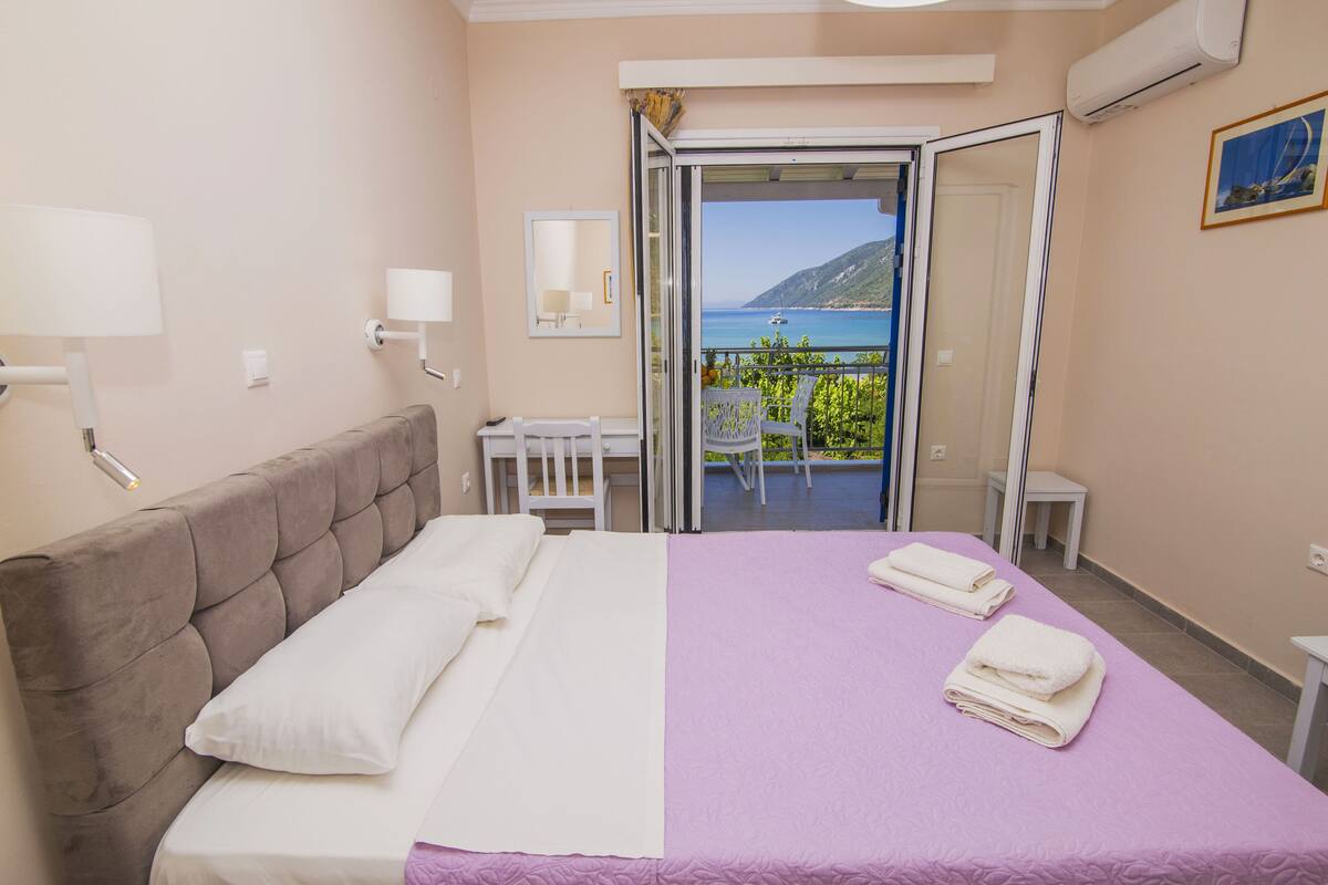 Una habitación de hotel con cama, balcón y vista al mar, además de una silla.