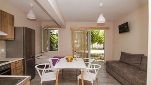 A modern kitchen with a dining area, a sofa, and a TV. - Nefeli (Lefkada)