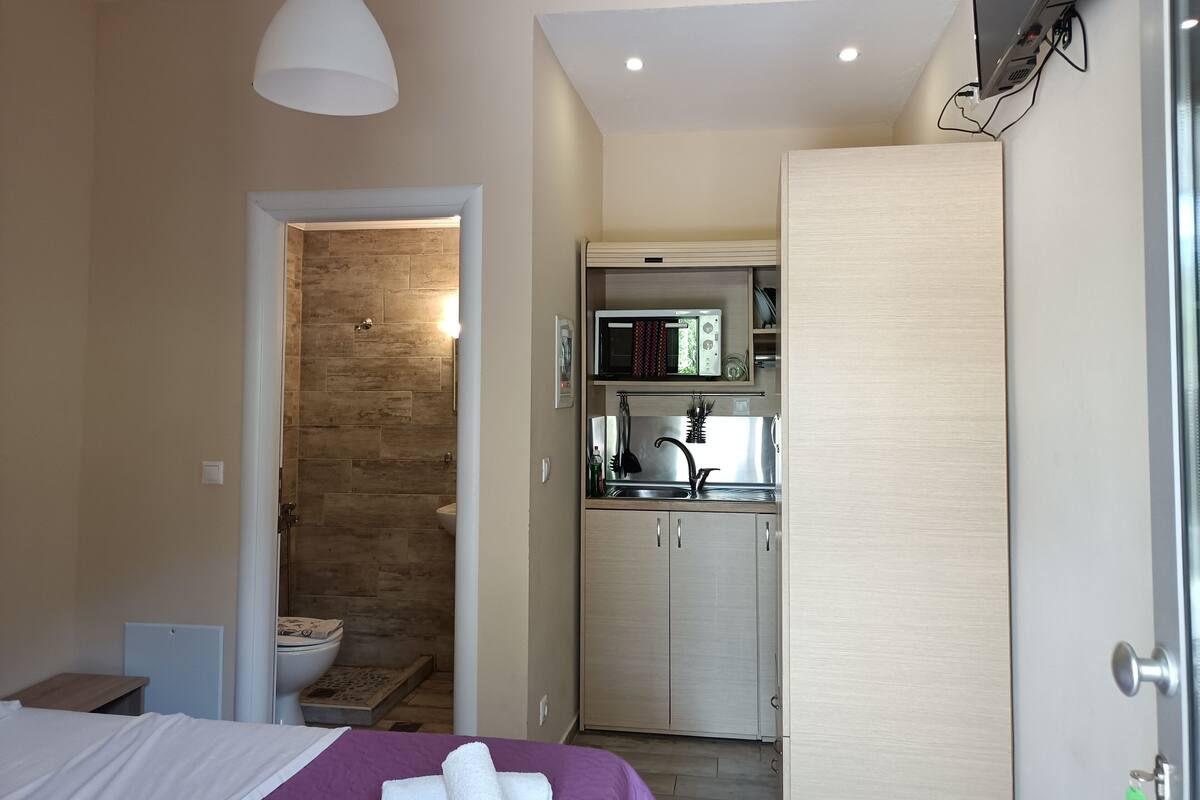 Una habitación de hotel pequeña con cama, baño y kitchenette.