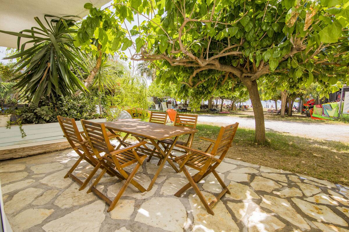 Un patio al aire libre con piso de piedra, mesa y sillas de madera.