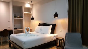 A hotel room with a bed, a desk, a chair, and a shelf with toiletries. - Narinfah Resort (Kaeng Krachan)