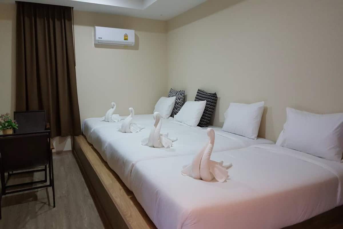 Quarto de hotel com duas camas, uma escrivaninha e uma planta em vaso.