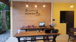 A modern room with a brick wall, a wooden table, and a computer monitor. - Narinfah Resort (Kaeng Krachan)