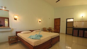 A bedroom with a wooden bed, two wall-mounted lights, a small wooden stool, and a mirror. - Sea Pearl Guest house (Candolim)