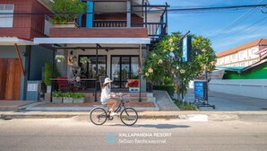 Un edificio de dos pisos con un balcón, una bicicleta estacionada adelante y un letrero.