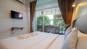 Habitación de hotel con cama, televisor de pantalla plana montado en la pared y ventana con cortinas.
