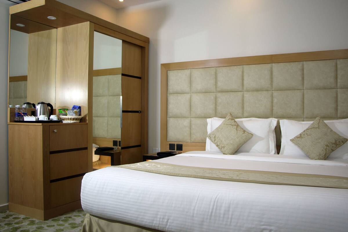 Ein Hotelzimmer mit Bett, Holzschrank, Nachttisch und Spiegel.