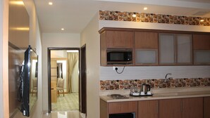 A modern kitchen with wooden cabinets, a microwave, and a coffee maker. - AlMuhaidb Residence Al Khafji (Al Khafji)