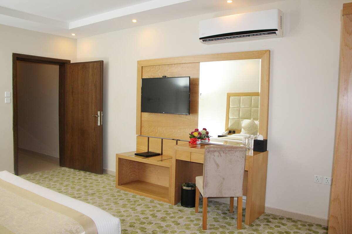 Ein Hotelzimmer mit einem Bett, einem Schreibtisch mit Stuhl, einem Fernseher und einer Klimaanlage.