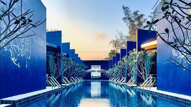 A swimming pool with a clear view of the water, surrounded by blue walls and plants. - Sea & Sea Villa Resort Sangaroon (Thap Sakae)