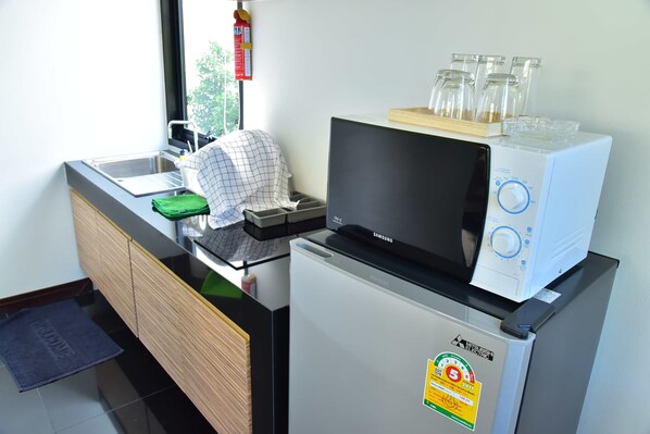 A compact kitchen with a microwave, refrigerator, and sink.