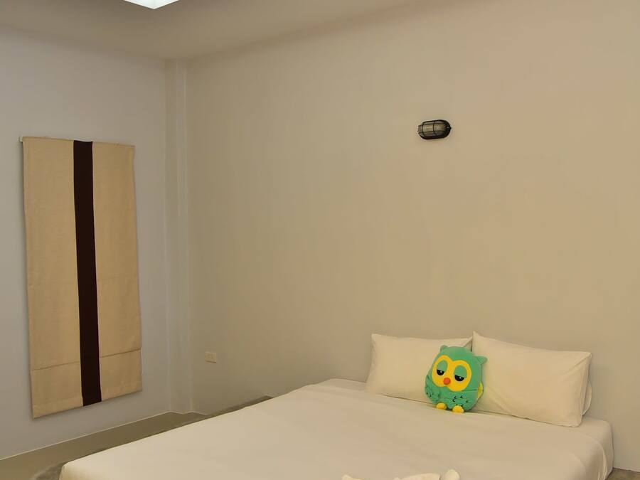 Ein Schlafzimmer mit Bett, einer Hängeleuchte, einer Wandleuchte und einem Kopfkissen mit einer Zeichentrickfigur.