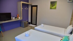 Habitación de hotel con dos camas, un escritorio con televisor, un mueble pequeño y una puerta.