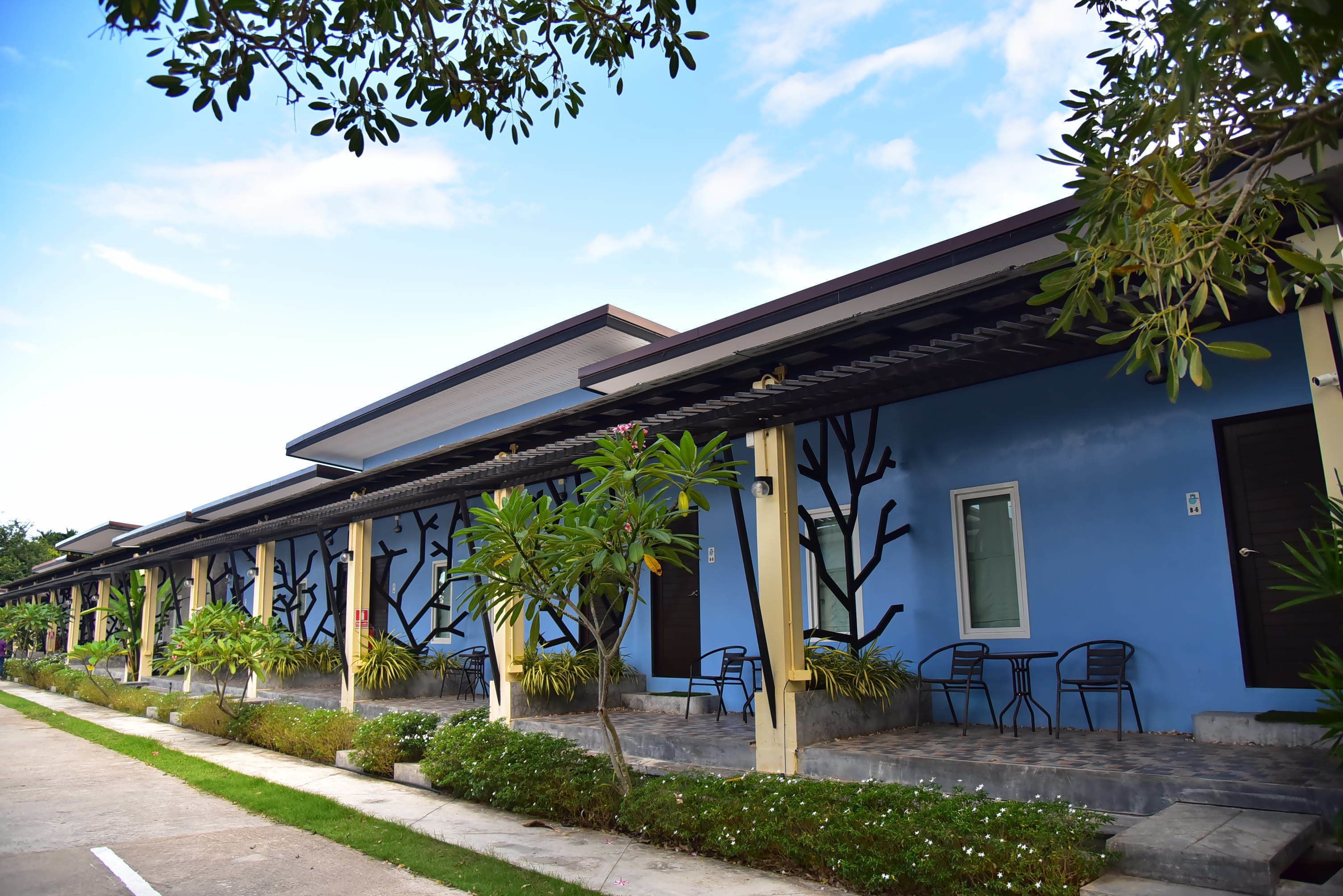 A row of blue buildings with outdoor seating and greenery.