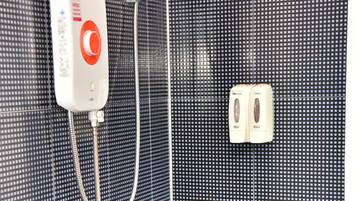 A shower area with a control panel, a handheld showerhead, and a wall-mounted faucet.