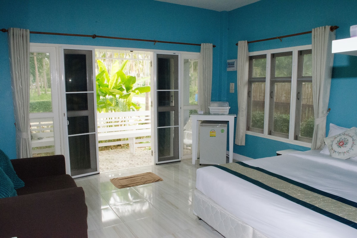 A room with a bed, a small desk, and a sliding glass door leading to an outdoor area.