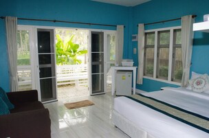 A room with a bed, a small desk, and a sliding glass door leading to an outdoor area.