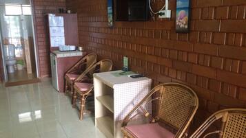 A restaurant with brick walls, wooden chairs, a tiled floor, and a TV mounted on the wall.