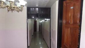 A hallway with a chandelier, a wooden door with a number, and a tiled floor. - Prumssy Hotel (Lekki)