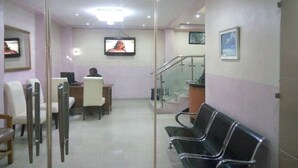 A waiting area with a reception desk, chairs, a television, and a staircase. - Prumssy Hotel (Lekki)