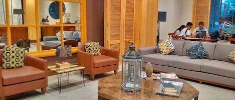 A modern lobby with leather sofas, a coffee table, and wooden paneling.