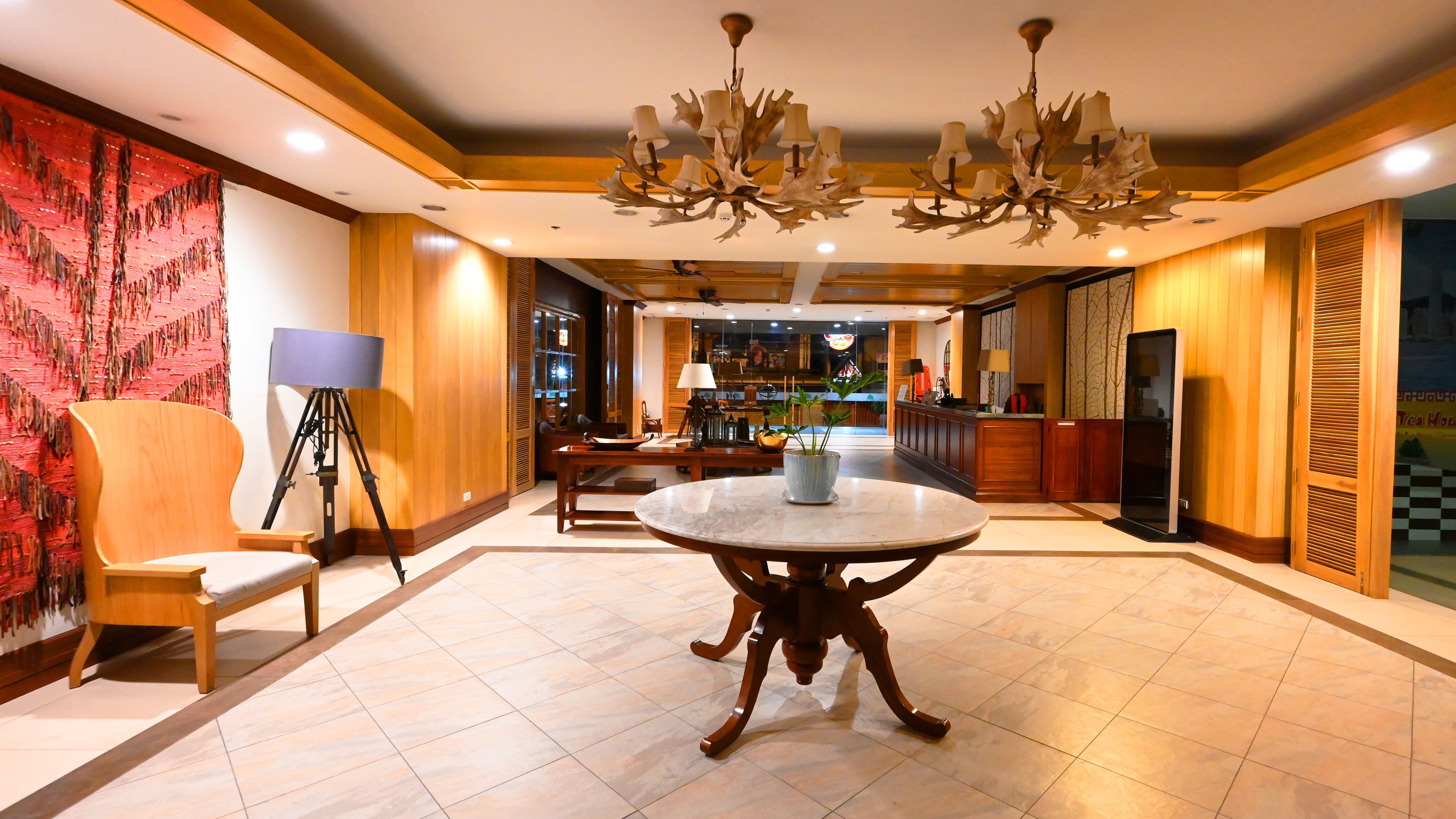 A spacious lobby with a round marble table, wooden paneling, and a chandelier.