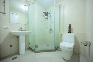 Ein Badezimmer mit Duschkabine, Standwaschbecken, Toilette und Spiegel.